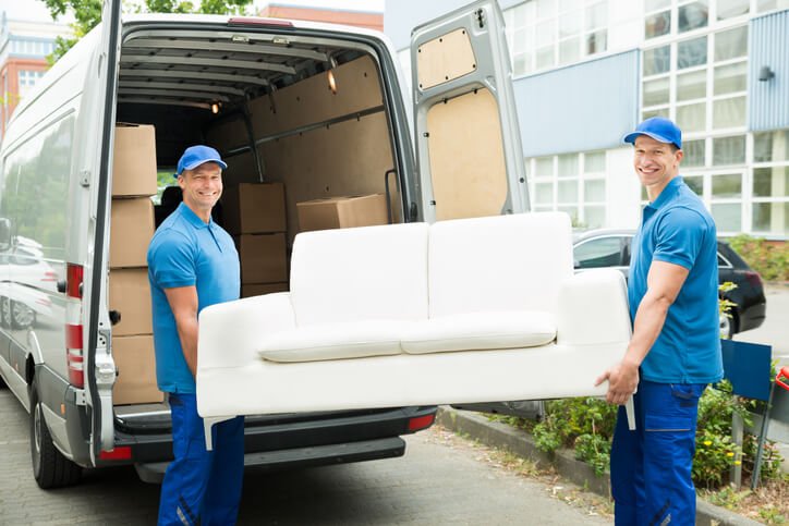 Two professional movers carrying a junk furniture into a transport van in Fort Lauderdale, FL
